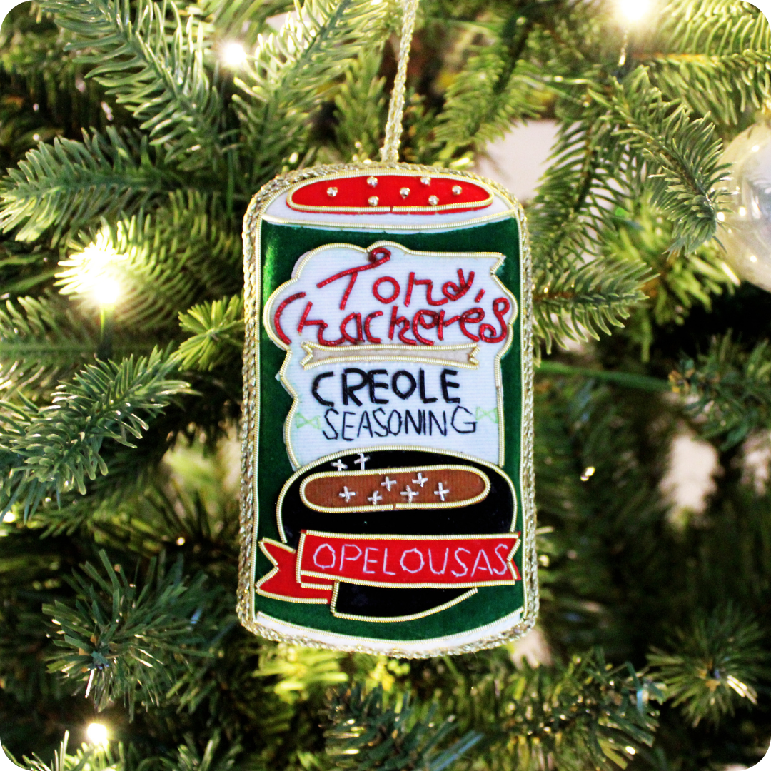 Festive ornament with beaded detailing in the shape of a Tony Chachere’s seasoning can hangs on the tree, positioned as a creole christmas gift.